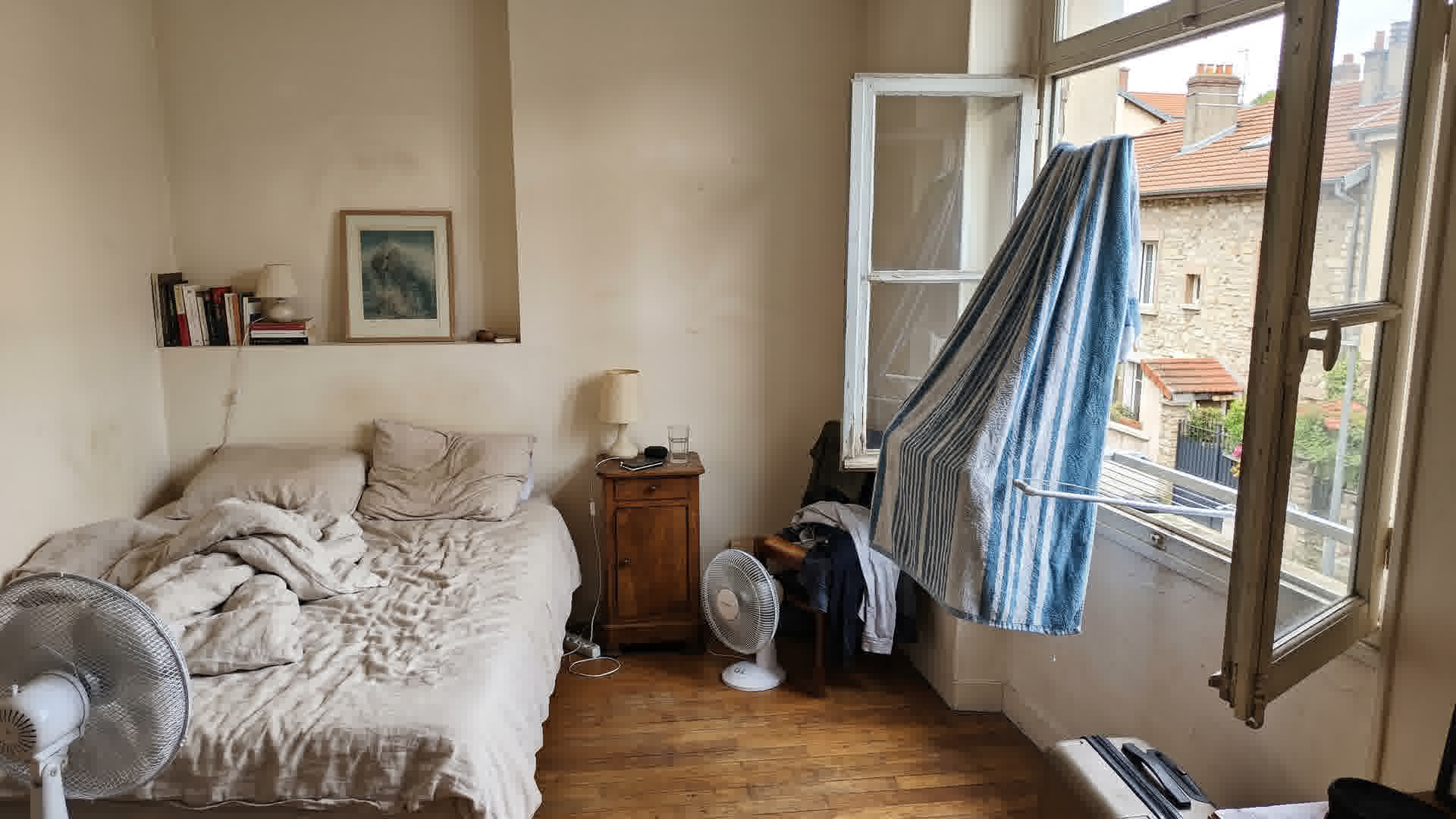 Serviette mouillée suspendue près d'une fenêtre ouverte dans une chambre française comme astuce de refroidissement estival