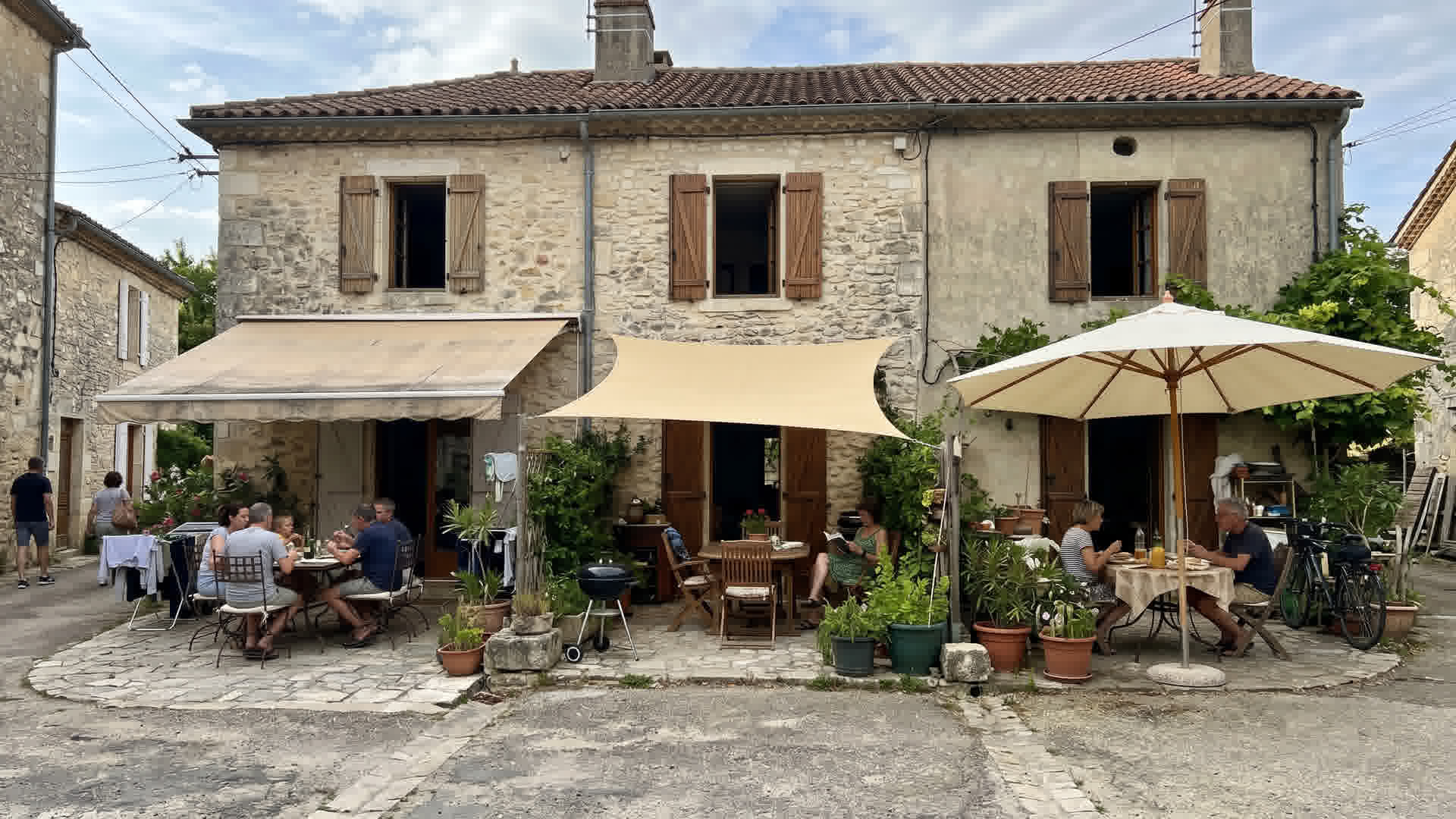 Différentes solutions d'ombrage visibles sur des maisons françaises voisines : store, voile, parasol
