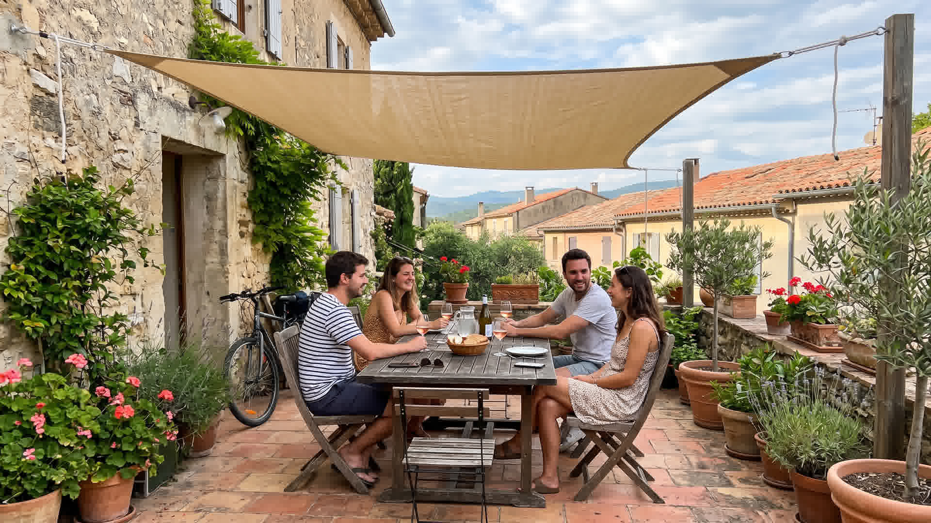 Voile d'ombrage triangulaire installé au-dessus d'une terrasse française avec table et chaises en dessous