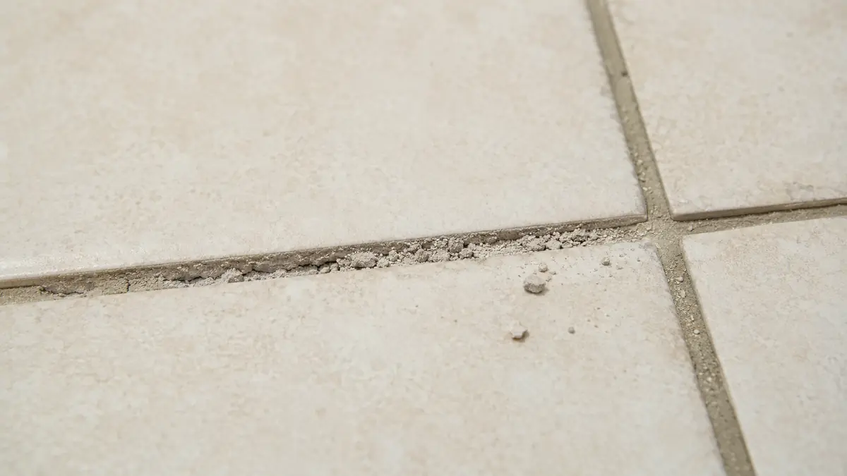 Joint de carrelage au sol devenu poudreux et creusé entre deux carreaux